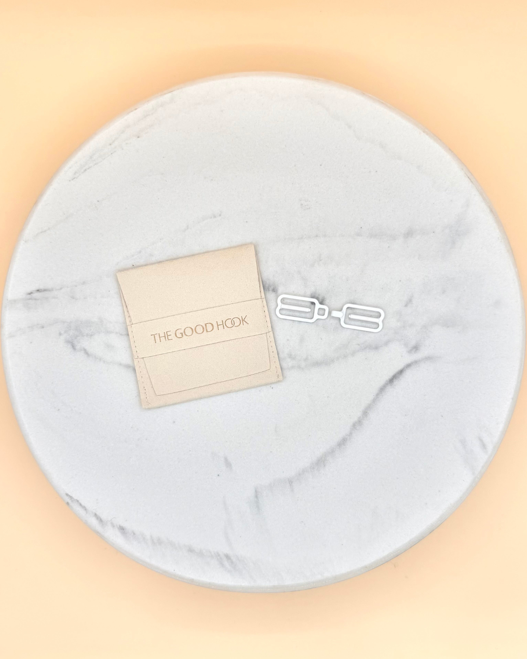 Round gray marble-like pad with a beige card and logo on a peach background